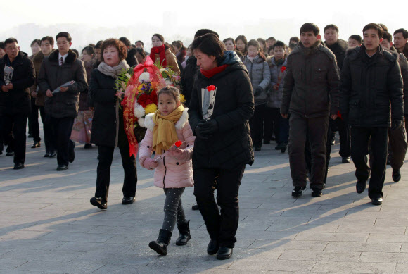 평양 시민들이 16일(현지시간) 김정일 국방위원장의 77돌 생일(광명성절)을 맞아 평양 만수대 김일성·김정일 동상에 꽃을 들고 참배하고 있다. AP 연합뉴스