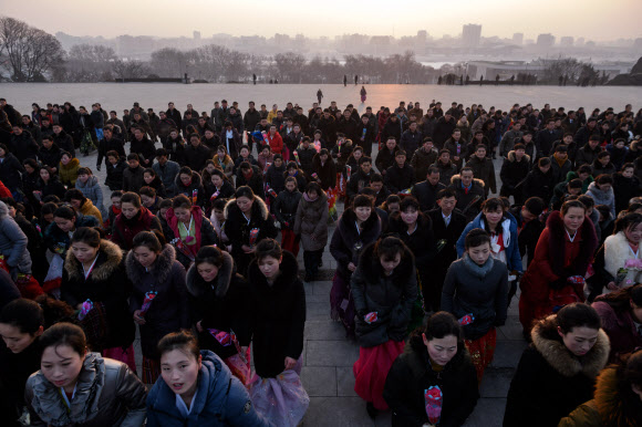 평양 시민들이 16일(현지시간) 김정일 국방위원장의 77돌 생일(광명성절)을 맞아 평양 만수대 김일성·김정일 동상에 꽃을 들고 참배하고 있다. AFP 연합뉴스