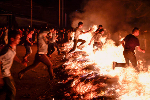 19일(현지시간) 중국 하이난성 하이커우에서 음력설 축제의 마지막을 알리는 정월 대보름 기념 행사에서 사람들이 모닥불 위를 뛰어넘고 있다. AFP 연합뉴스