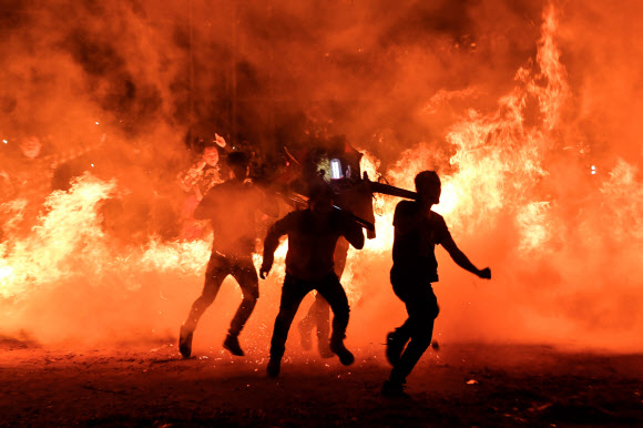 19일(현지시간) 중국 하이난성 하이커우에서 음력설 축제의 마지막을 알리는 정월 대보름 기념 행사에서 사람들이 신의 동상을 들고 모닥불 위를 뛰어넘고 있다. AFP 연합뉴스