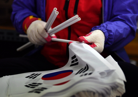서울 성동구 동영산업 공장에서 한 직원이 손 태극기에 깃대를 넣는 작업을 하고 있다.