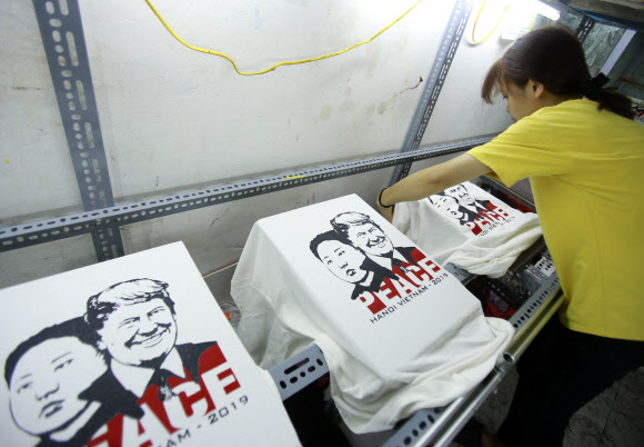 21일(현지시간) 베트남 하노이의 한 티셔츠 가게에서 북미 정상회담 개최를 기념해 트럼프 대통령과 김정은 국무위원장의 얼굴이 들어간 티셔츠를 제작하고 있다. AP 연합뉴스