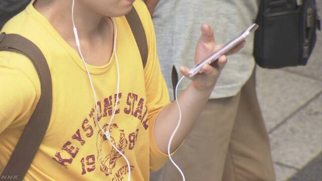 스마트폰에서 이어진 이어폰으로 음악을 듣고 있는 한 일본 젊은이.