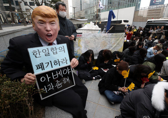 27일 오후 서울 종로구 주한 일본대사관 앞에서 열린  ‘일본군 성노예제 문제 해결을 위한 정기 수요시위’에서 트럼프 마스크를 쓴 한 참가자가 ‘한일합의 폐기하라’가 적힌 손피켓을 들고 있다. 2019.2.27  연합뉴스