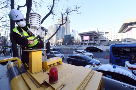서울 광화문에서 Kt 직원이 공중전화부스 위에 미세먼지를 측정하기 위해 설치한 공기질측정기를 점검하고 있다. 2019. 3. 7 정연호 기자 tpgod@seoul.co.kr