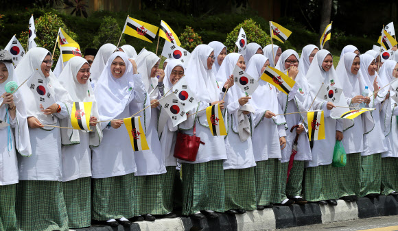 11일 오전(현지시간) 브루나이 왕궁 앞 도로에서 태극기와 브루나이 국기를 든 학생들이 문재인 대통령과 김정숙 여사 행렬을 환영하고 있다.  2019.3.11  연합뉴스