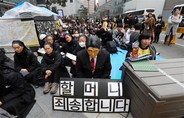 20일 서울 종로구 옛 일본대사관 앞에서 열린 제1379차 일본군성노예제 문제해결을 위한 정기 수요시위에서 한 참가자가 아베 신조 일본 총리의 가면을 쓰고 ‘할머니 죄송합니다’ 팻말과 함께 고개를 숙이고 있다. 2019.3.20 뉴스1