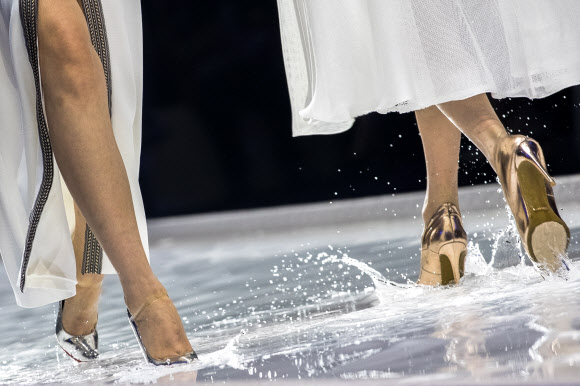 모델들이 26일(현지시간) 중국 베이징에서 열린 ‘차이나 패션 위크(China Fashion Week)’중 디자이너 그레이스 첸(Grace Chen) 패션쇼에서 물로 가득찬 바닥을 조심스럽게 걷고 있다. EPA 연합뉴스