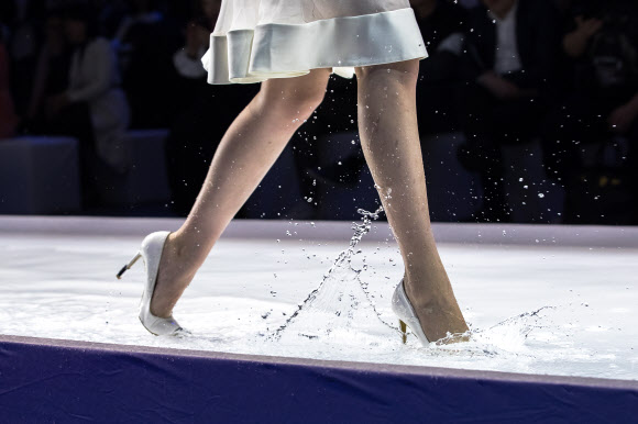 모델이 26일(현지시간) 중국 베이징에서 열린 ‘차이나 패션 위크(China Fashion Week)’중 디자이너 그레이스 첸(Grace Chen) 패션쇼에서 물로 가득찬 바닥을 조심스럽게 걷고 있다. EPA 연합뉴스