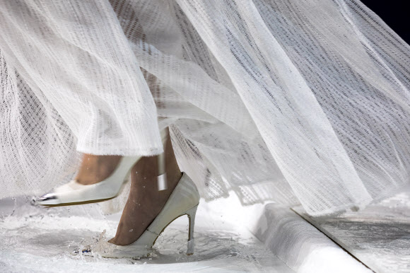 모델이 26일(현지시간) 중국 베이징에서 열린 ‘차이나 패션 위크(China Fashion Week)’중 디자이너 그레이스 첸(Grace Chen) 패션쇼에서 물로 가득찬 바닥을 조심스럽게 걷고 있다. EPA 연합뉴스