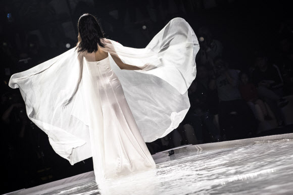 모델이 26일(현지시간) 중국 베이징에서 열린 ‘차이나 패션 위크(China Fashion Week)’중 디자이너 그레이스 첸(Grace Chen) 패션쇼에서 물로 가득찬 바닥을 조심스럽게 걷고 있다. EPA 연합뉴스