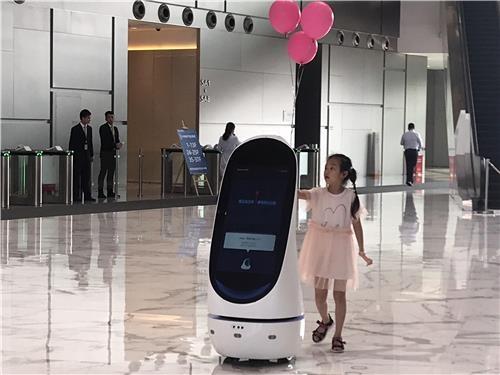 중국 인터넷 기업 텐센트의 선전 본사 로비에 있는 로봇이 어린이에게 길을 안내하고 있다.