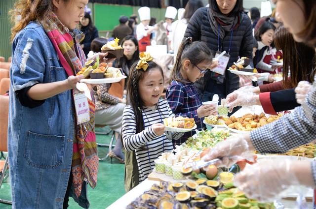 지난해 11월 동작구민회관에서 열린 ‘어린이집 조리사 요리 페스티벌’에 참가한 학부모와 어린이가 시식을 위해 조리사가 정성껏 차려 낸 음식을 접시에 담으며 즐거워하고 있다. <br>동작구 제공