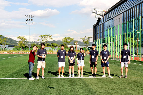 한국항공대 항공캠프에 참가한 학생들이 드론전문가로부터 설명을 들으며 직접 드론을 조종해보고 있다.