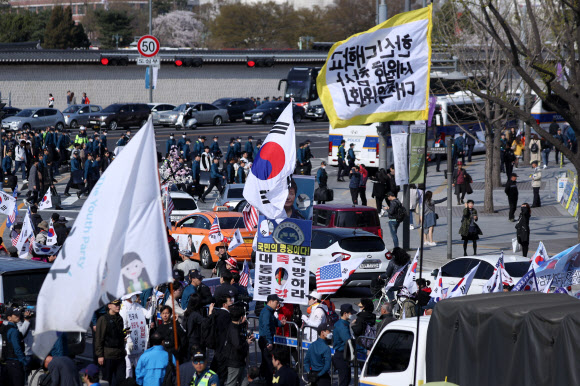 세월호 참사 5주기를 사흘 앞둔 13일 오후 서울 종로구 광화문 광장에서 추모행사가 펼쳐지는 가운데 태극기 집회를 마친 보수단체 참가자들이 행사장 주변을 행진하고 있다. 2019.4.13  연합뉴스