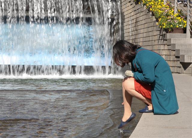 16일 오전 서울 청계광장에서 한 시민이 물에 발을 담그고 있다. 기상청은 이날 한낮 최고 기온이 대부분 20도를 웃돌면서 봄기운이 가득할 것으로 예보했다. 2019.4.16 뉴스1