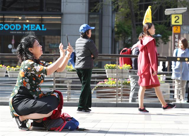16일 오전 서울 청계광장에서 한 외국인 관광객이 반팔 차림으로 사진을 찍고 있다. 기상청은 이날 한낮 최고 기온이 대부분 20도를 웃돌면서 봄기운이 가득할 것으로 예보했다. 2019.4.16 뉴스1