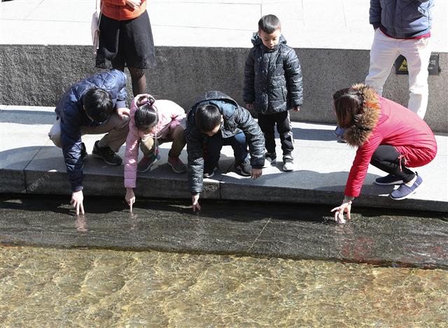 16일 오전 서울 청계천에서 외국인 가족이 물에 손을 담그고 있다. 기상청은 이날 한낮 최고 기온이 대부분 20도를 웃돌면서 봄기운이 가득할 것으로 예보했다. 2019.4.16 뉴스1