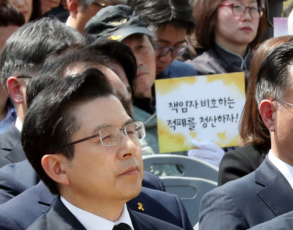 16일 오전 인천시 부평구 인천가족공원 세월호일반인희생자추모관 앞에서 열린 ‘세월호 참사 일반인 희생자 5주기 추모식’에서 한 시민단체가 추모식에 참석한 황교안 자유한국당 대표 뒤편에서 세월호 참사 책임자 수사 처벌을 촉구하는 피켓을 들고 있다. 2019.4.16  연합뉴스