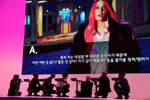 기자간담회 도중 가수 할시의 인터뷰 영상이 나오자 BTS가 취재진을 위해 바닥에 내려앉아 영상을 보고 있다.<br>연합뉴스