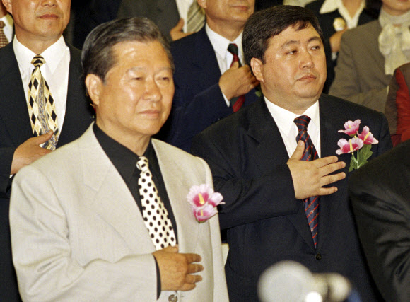 20일 별세한 김홍일(오른쪽) 전 민주당 의원이 15대 총선 당선 직후인 1996년 4월 16일 국민회의 당선자대회에서 아버지인 김대중 당시 국민회의 총재와 함께 국기에 대한 경례를 하고 있다.  연합뉴스