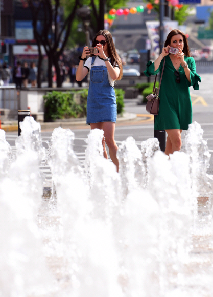 초여름 날씨를 보인 22일 서울광장에서 외국관광객들이 분수대를 찍고 있다.  2019. 4. 22  정연호 기자 tpgod@seoul.co.kr