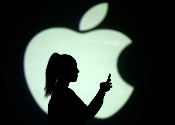 지난해 3월 미국 캘리포니아주 쿠퍼티노의 애플 본사 로고 그림자 사이로 모바일 이용자의 그림자가 선명히 보인다. 쿠퍼티노 로이터 연합뉴스