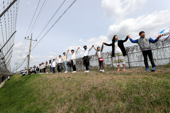 철책 앞에서 마주 잡은 손