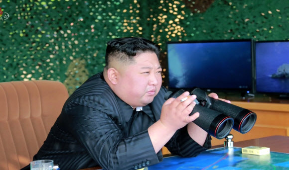 김정은 북한 국무위원장이 전날 동해 해상에서 진행된 화력타격 훈련 모습을 담배를 오른손에 낀 채로 망원경을 들어 보려고 하고 있다. 5일 조선중앙TV가 보도했다. 연합뉴스