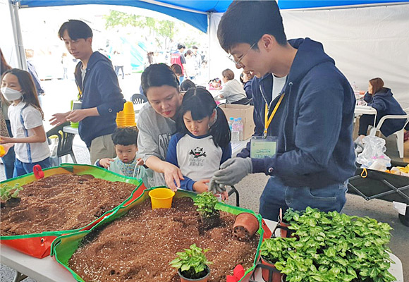 지난 4일 노원역 노해로 일대에서 열린 어린이날 축제 행사장에서 노원그린캠퍼스타운사업단의 서포터즈(오른쪽)가 한 가족의 ‘미니화분 만들기’를 돕고 있다.