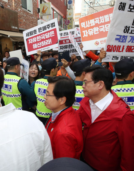 자유한국당 황교안 대표가 14일 오후 충북 청주시 상당구 한 커피점에서 학부모 간담회를 마치고 나가던 중 민주노총 충북지역본부 조합원들이 자유한국당 해체를 요구하며 시위를 벌이자 경찰의 도움을 받아 빠져나가고 있다. 2019.5.14  연합뉴스