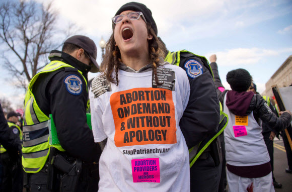 한 낙태 찬성 운동가(가운데)가 2015년 1월 미국 워싱턴DC의 미 대법원 앞에서 낙태 반대 집회인 ‘생명을 위한 /행진’에 반대하며 길을 막았다가 경찰에 연행되고 있다. AFP 연합뉴스 
