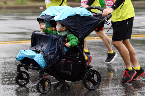 19일 쏟아지는 빗줄기 속에서 가족 단위 참가자가 여럿 눈에 띄었다. 한 남성이 유모차를 탄 두 아이와 레이스를 즐기는 모습. 박윤슬 기자 seul@seoul.co.kr
