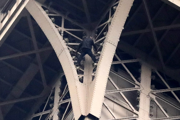한 남성이 20일(현지시간) 프랑스 파리의 에펠탑에 매달려 있다. AP 연합뉴스