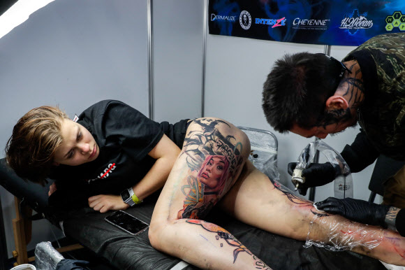 26일(현지시간) 러시아 소콜니키 전시 센터에서 열린 ‘제10회 국제 모스크바 타투 대회’에서 타투 아티스트가 문신 새기는 작업을 하고 있다. 타스 연합뉴스