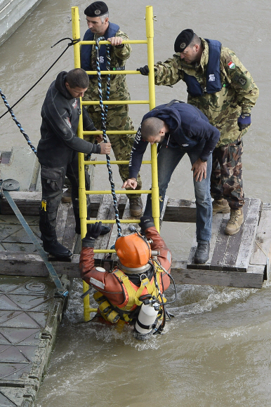 A diver descends a ladder to dive to the wreckage as rescuers work to prepare the recovery of the capsized boat under Margaret Bridge in Budapest, Hungary, Thursday, May 30, 2019, after a sightseeing boat carrying 33 South Korean tourists collided with a large river cruise ship on River Danube near the bridge the night before. (Tamas Kovacs/MTI via AP)