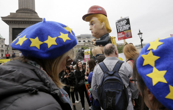 4일(현지시간) 영국 런던 중심가에서 시위대가 황금변기에 앉은 도널드 트럼프 로봇을 옮기고 있다. 이날 런던 트라팔가 광장에는 반 트럼프 시위가 열려 트럼프의 인종주의에 항의하고 “트럼프에게 노(No)라고 해야한다”는 구호가 나왔다. 영국을 국빈방문한 트럼프 미국 대통령은 이날 테리사 메이 총리와 회담을 갖고 새로운 동맹을 강조하는 한편 중국 통신장비업체 화웨이에 대한 제재 등을 요구한 것으로 알려졌다.  2019.6.4 AP 연합뉴스