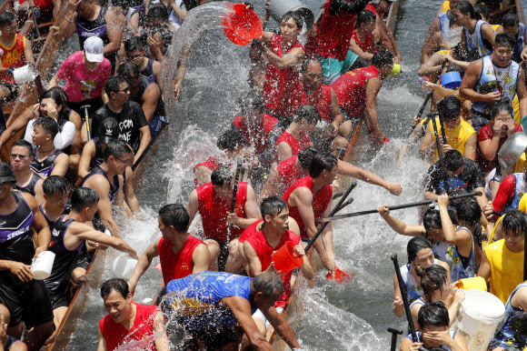 참가자들이 7일(현지시간) 홍콩 전역에서 열리는 중국 드래곤 보트 축제를 기념하는 행사의 일환으로 드래곤 보트에서 서로 물을 끼얹고 있다. 드래곤 보트 경주는 기원전 277년 정부의 부패를 비판했던 고대 중국 학자 정치가인 추유안을 기념하고 있다. 했다. AP 연합뉴스