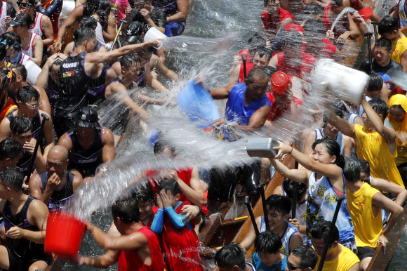 참가자들이 7일(현지시간) 홍콩 전역에서 열리는 중국 드래곤 보트 축제를 기념하는 행사의 일환으로 드래곤 보트에서 서로 물을 끼얹고 있다. 드래곤 보트 경주는 기원전 277년 정부의 부패를 비판했던 고대 중국 학자 정치가인 추유안을 기념하고 있다. 했다. AP 연합뉴스
