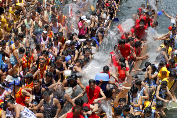 참가자들이 7일(현지시간) 홍콩 전역에서 열리는 중국 드래곤 보트 축제를 기념하는 행사의 일환으로 드래곤 보트에서 서로 물을 끼얹고 있다. 드래곤 보트 경주는 기원전 277년 정부의 부패를 비판했던 고대 중국 학자 정치가인 추유안을 기념하고 있다. 했다. AP 연합뉴스