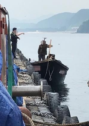 지난 15일 북한 선원 4명이 탄 어선이 연안에서 조업 중인 어민의 신고로 발견됐다는 정부 당국의 발표와 달리 삼척항 부두에 정박했다고 KBS가 18일 보도했다. 사진은 당시 북한 선원들이 삼척항 부두에 정박한 뒤 주민과 대화를 나누는 모습. 2019.6.19 뉴스1