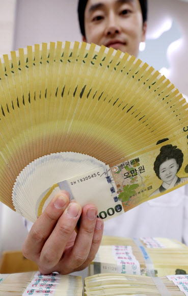 한국은행이 2009년 6월 23일 새로운 최고 액면 은행권 5만 원권을 발행한 지 올해로 10주년이 됐다. 이후 5만 원권이 중심 권종으로 자리 잡게 되면서 초기 문제로 지적됐던 색상 혼돈, 위폐 우려, 낮은 환수율 문제는 대부분 해소된 것으로 나타났다. 19일 서울 KEB하나은행에서 직원이 오만원권을 들어보이고 있다.  2019.6.19  연합뉴스