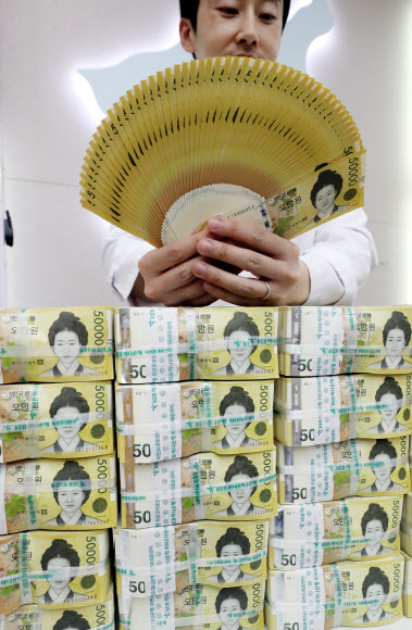 한국은행이 2009년 6월 23일 새로운 최고 액면 은행권 5만 원권을 발행한 지 올해로 10주년이 됐다. 이후 5만 원권이 중심 권종으로 자리 잡게 되면서 초기 문제로 지적됐던 색상 혼돈, 위폐 우려, 낮은 환수율 문제는 대부분 해소된 것으로 나타났다. 19일 서울 KEB하나은행에서 직원이 오만원권을 들어보이고 있다.  2019.6.19  연합뉴스