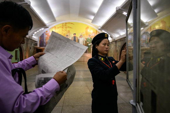 지하철 안내원이 19일(현지시간) 북한 평양의 한 지하철역 신문 가판대 신문을 교체하고 있다. AFP 연합뉴스
