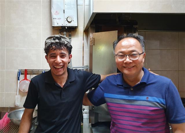 예멘 난민 요리사 압둘라와 홍주민 한국디아코니아 협동조합 대표가 경기 수원의 ‘YD케밥하우스´ 주방에서 어깨동무를 하며 웃고 있다.