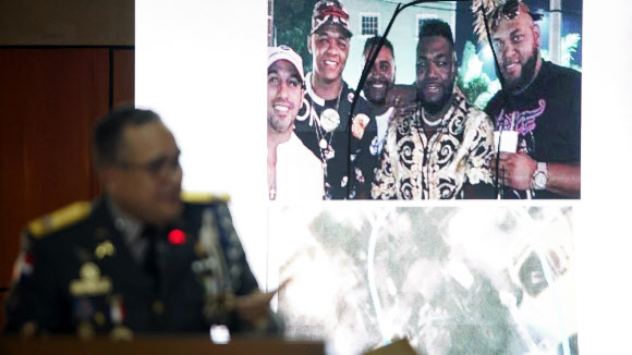 Director of the National Police, General Ney Aldrin Bautista Almonte, projects a photograph taken of former Boston batter David Ortiz, second from right, with others on the night he was shot in Santo Domingo, Dominican Republic, Wednesday June 19, 2019. According to Bautista Almonte, Ortiz was shot by a gunman who mistook him for the real target, Sixto David Fern찼ndez, not in the projected photo, who was seated at the same table with the former baseball star on the night of June 9. (AP Photo/Roberto Guzman)