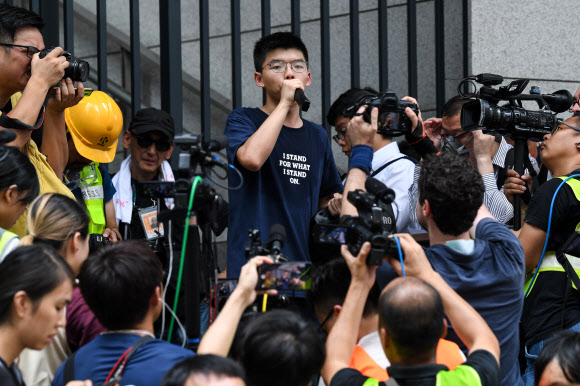 홍콩 우산 혁명의 주역 조슈아 웡이 21일 홍콩 입법원 앞에서 시위를 하던 이들에게 경찰본부 앞으로 행진할 것을 호소하고 있다. 홍콩 AFP 연합뉴스