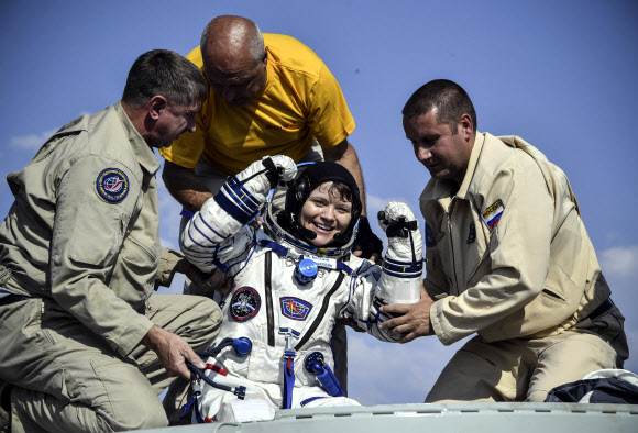 미국 우주인 앤 매클레인(가운데)이 착륙 직후 러시아 우주국 구조팀의 도움을 받아 우주캡슐에서 나오는 모습. 제즈카즈간 AP 연합뉴스