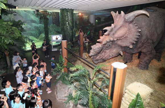 26일 오전 서울 강서구 롯데백화점 김포공항점 쥬라기 월드 특별전 전시장에서 어린이들이 공룡을 살펴보고 있다.  이번 특별전은 롯데백화점이 미국의 유니버셜 사와 손잡고 쥬라기 월드를 재현한 전시로 전세계 5번째이자 아시아 최초로 진행된다.  쥬라기 월드 영화의 배경인 누블라 섬을 재현해 티라노사우르스 등 약 7종의 대형 공룡을 애니메트로닉스 기술을 통해 움직이게 만들었다. 2019. 06.26. 박지환 기자 popocar@seoul.co.kr