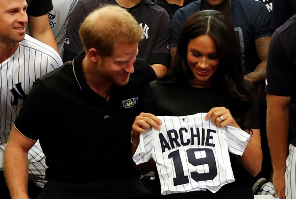 영국 해리 왕자와 메건 마클 왕자비가 뉴욕 양키스로부터 선물 받은 아들 아치의 유니폼을 들어 보이며 즐거워하고 있다. 런던 로이터 연합뉴스